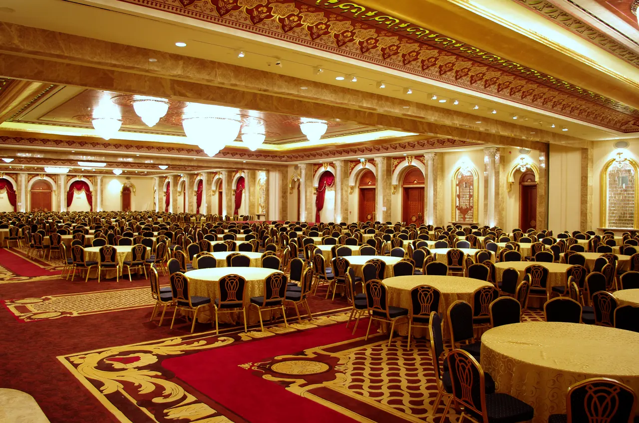Mardan Palace — Ballroom with red carpet, round tables and chandeliers