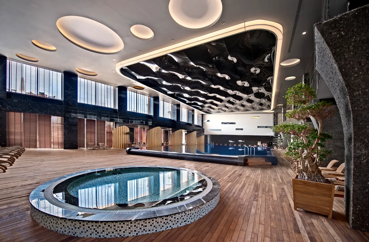 Maxx Royal Belek — Indoor pool hall with round jacuzzi and undulating ceiling