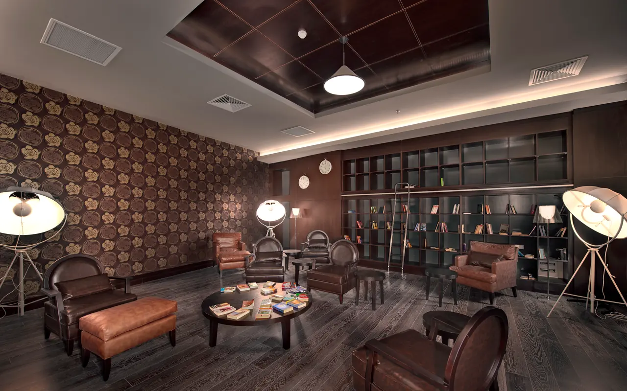 Maxx Royal Belek — Reading lounge with patterned wallpaper, leather armchairs and lamps