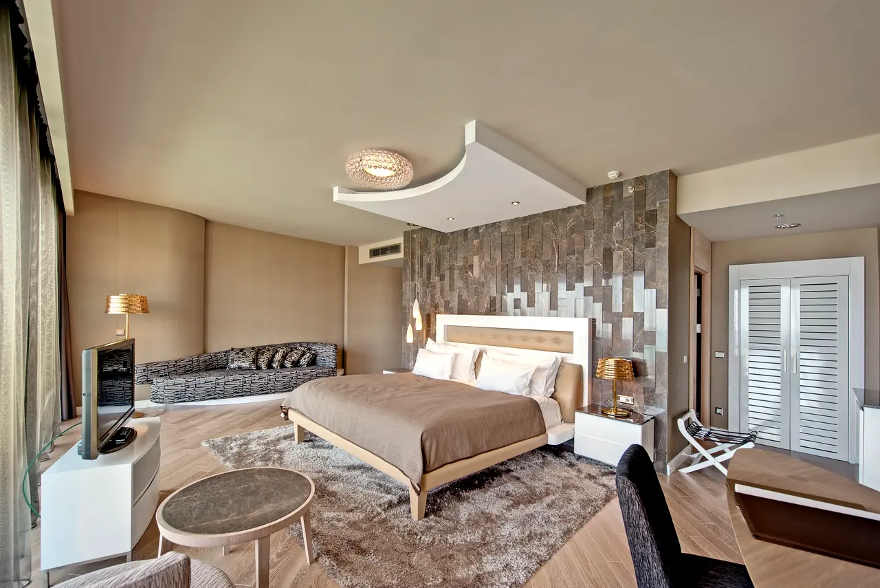 Maxx Royal Belek — Bedroom with textured headboard wall and seating corner