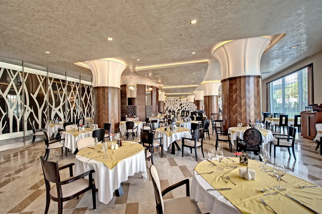 Maxx Royal Belek — Restaurant with branch-patterned panels and white column capitals