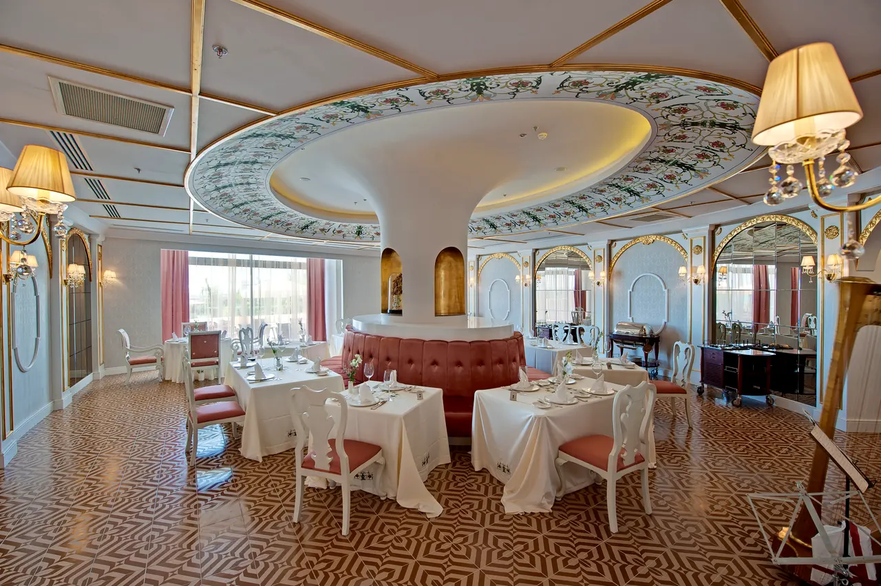 Maxx Royal Belek — Restaurant with a domed ceiling and white-laid tables