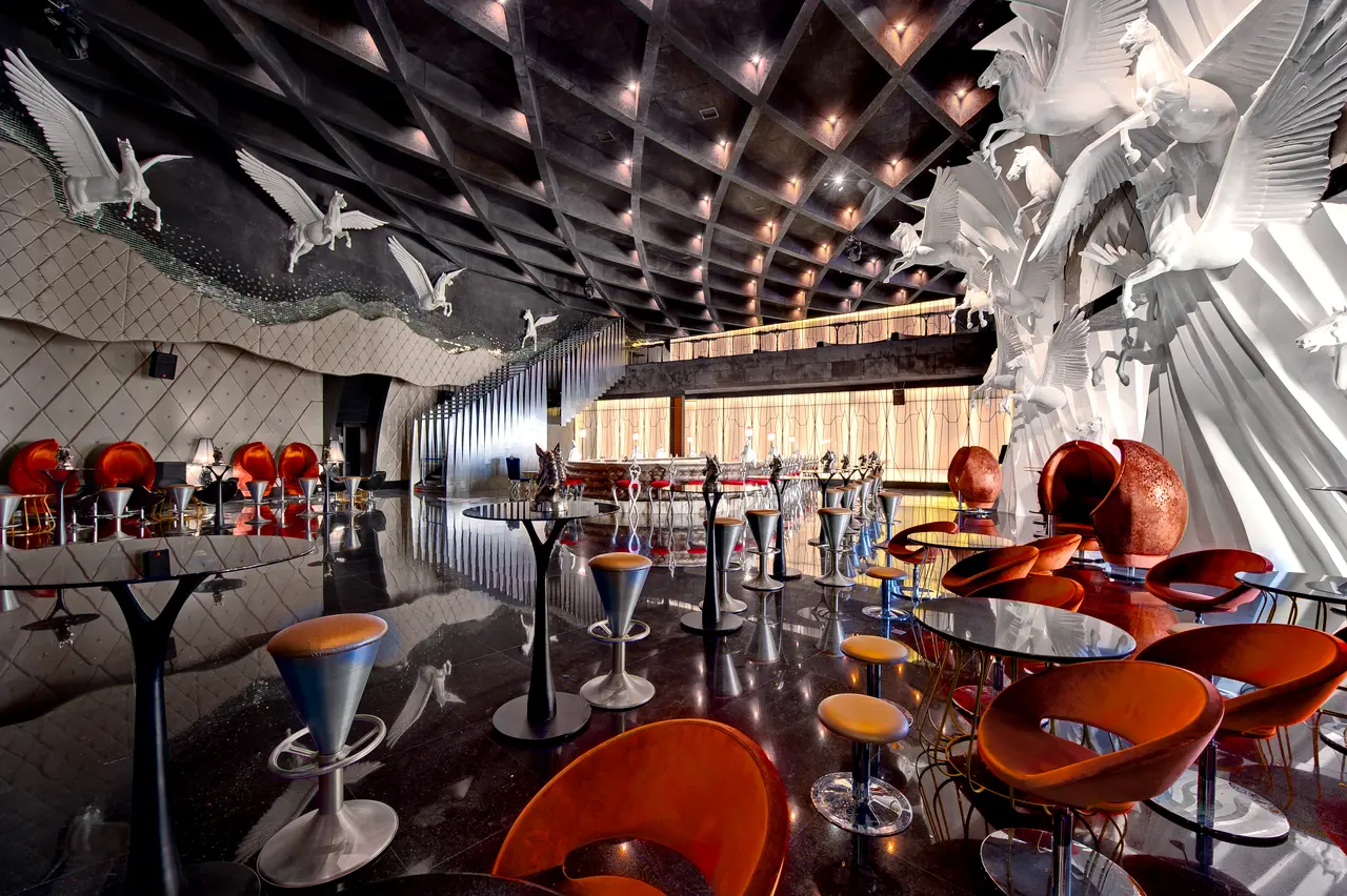 Maxx Royal Belek — Bar with bird sculptures, orange chairs and high tables