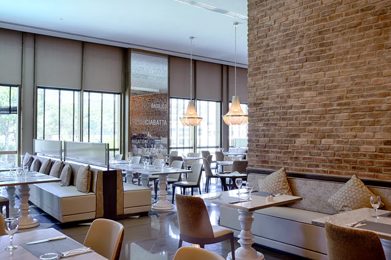 Rixos Premium Belek — Restaurant with brick wall, sofa booths and chandeliers