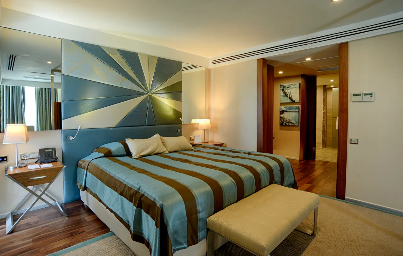 Rixos Premium Belek — Bedroom with radial-patterned headboard and striped cover