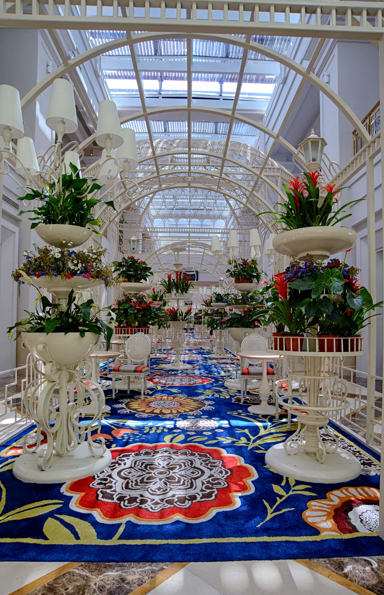 Rixos Premium Belek — Glass-roofed gallery with flower stands and patterned carpet